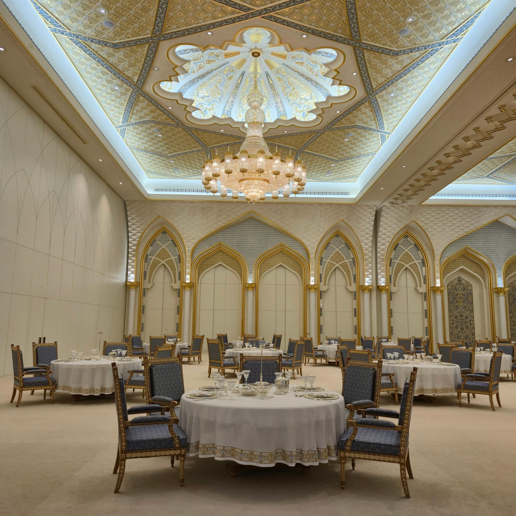 Elegant ballroom with round tables and an ornate ceiling